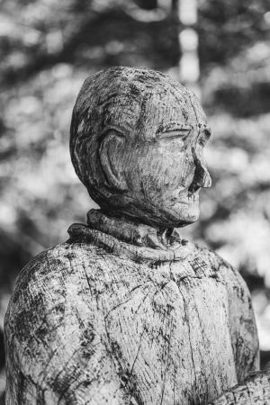 Portraitaufnahme einer Holzskulptur eines Wanderers, der sich ausruht