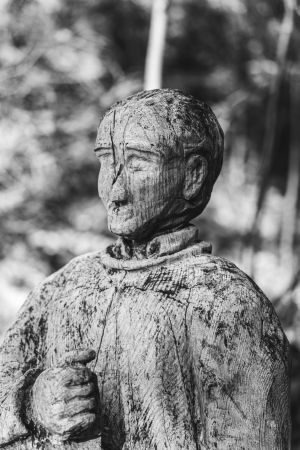 Portraitaufnahme einer Holzskulptur eines Wanderers, der sich ausruht