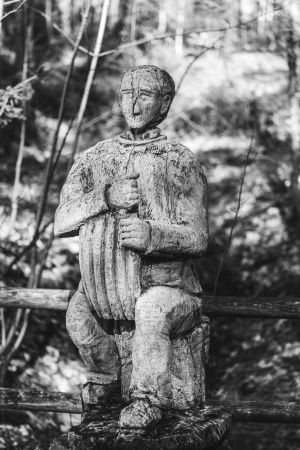 Holzskulptur eines Wanderers, der sich ausruht